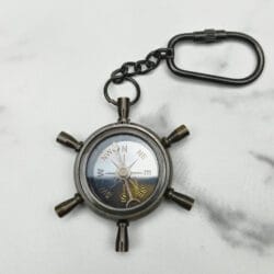 Functional shipwheel compass keychain with a white compass face and a black antique brass finish.