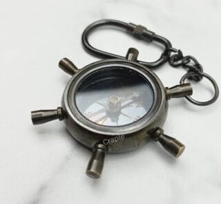 Nautical shipwheel compass keychain made from solid brass with a black antique finish and a secure carabiner clip.