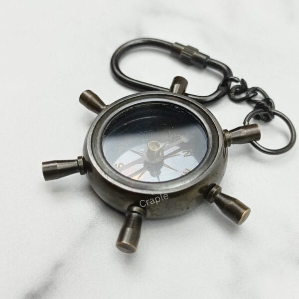 Nautical shipwheel compass keychain made from solid brass with a black antique finish and a secure carabiner clip.