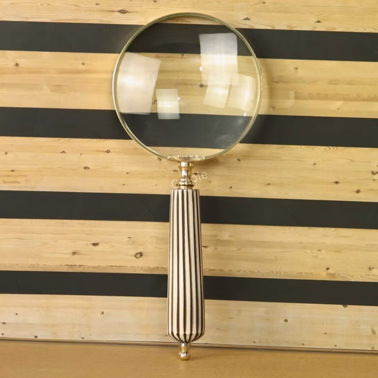 Elegant handheld magnifying glass with 5X magnification, a polished brass frame, and a vintage black and white striped handle.