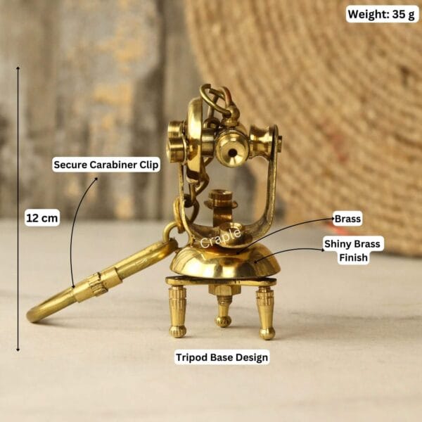 Brass theodolite keychain with labeled dimensions: 12 cm length, 35g weight, and tripod base design.