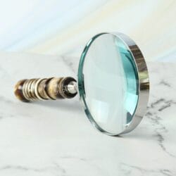 Handheld magnifying glass featuring a 5X lens, a polished nickel-finish frame, and a decorative turned resin handle.