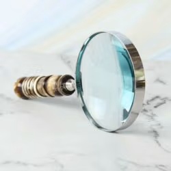 Handheld magnifying glass featuring a 5X lens, a polished nickel-finish frame, and a decorative turned resin handle.