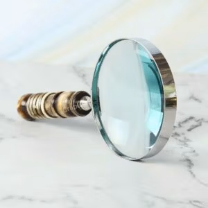 Handheld magnifying glass featuring a 5X lens, a polished nickel-finish frame, and a decorative turned resin handle.