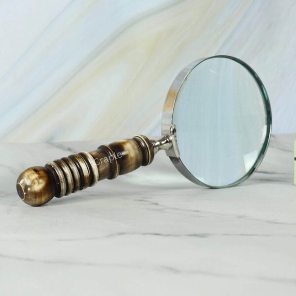 Close-up view of the intricately turned resin handle and the sturdy nickel-plated frame of a reading magnifier.