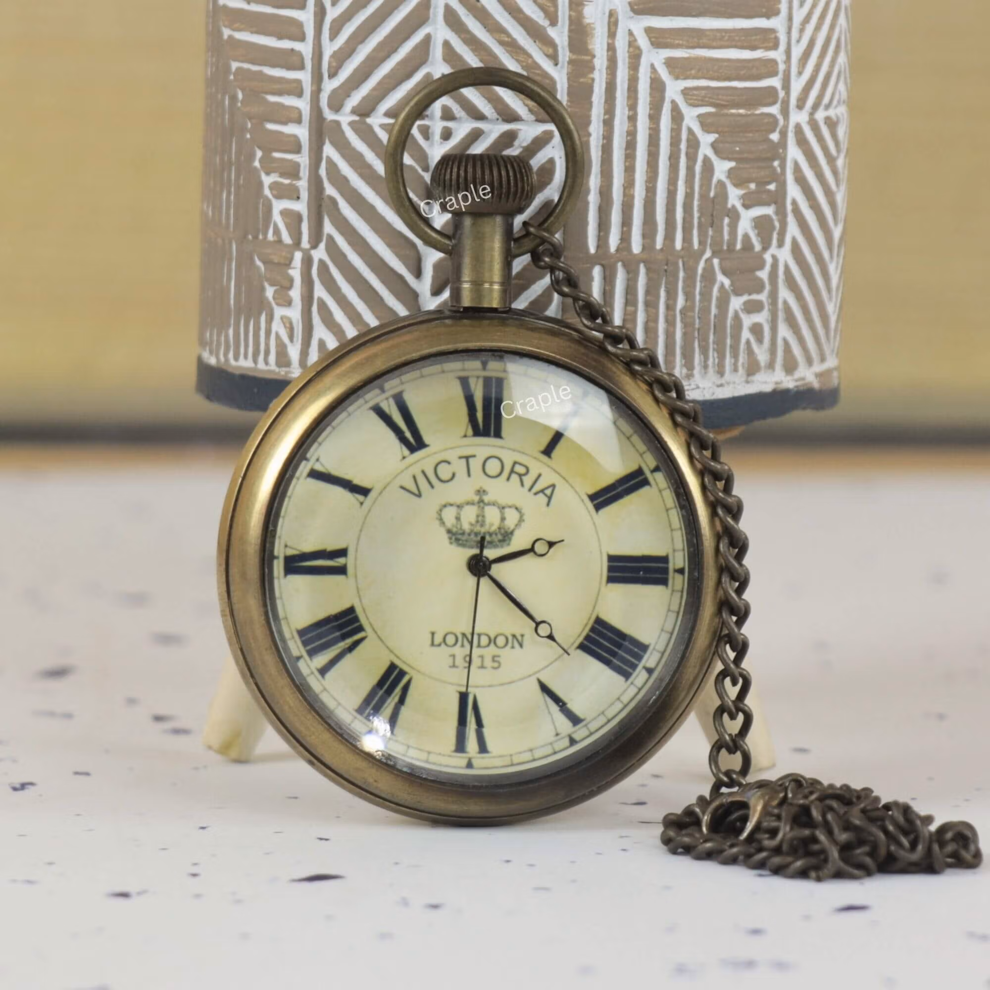 Antique brass 'Victoria London 1915' pocket watch with Roman numerals and a crown logo on the dial.