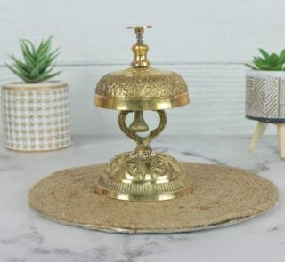Vintage handcrafted brass call bell with an engraved top and ornate stand, for hotel or reception desk decor.