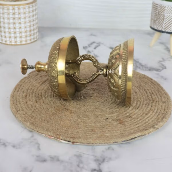 The internal clapper mechanism of the antique brass reception bell, shown with the bell lying on its side.