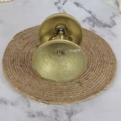 Top-down view of the ornate brass call bell, highlighting the detailed engraving on the bell and the push-button plunger.