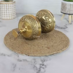 The engraved floral pattern on the side of the vintage brass hotel bell, shown in a detailed close-up view.