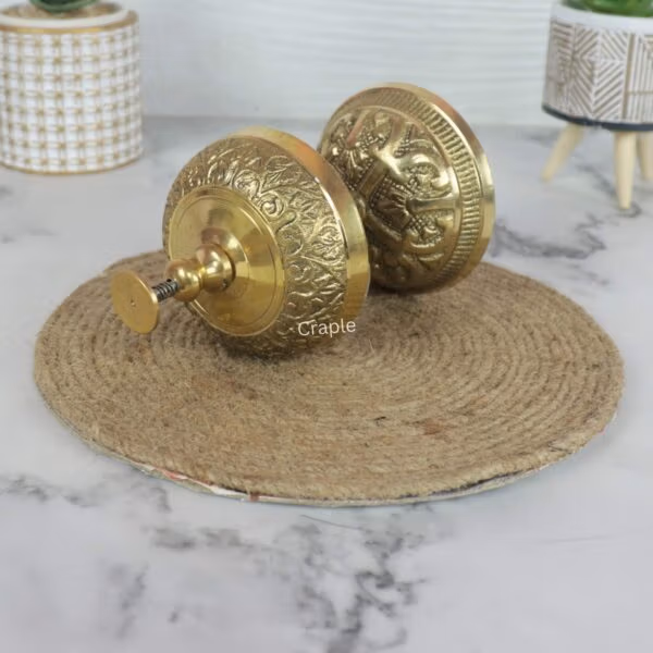 The engraved floral pattern on the side of the vintage brass hotel bell, shown in a detailed close-up view.