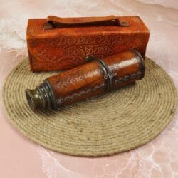 Vintage leather-wrapped brass telescope and its embossed case, styled on a coiled jute rope for a nautical theme.