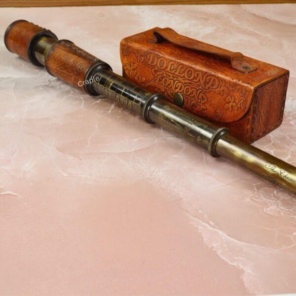 A fully extended nautical brass spyglass with a black antique finish and leather-wrapped barrel.