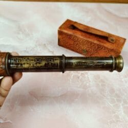 Detailed close-up of the intricate etching on the brass barrel of the vintage Chessmaker telescope.