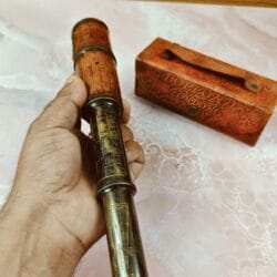 The leather-wrapped telescope being held in hand to demonstrate its size and comfortable grip.