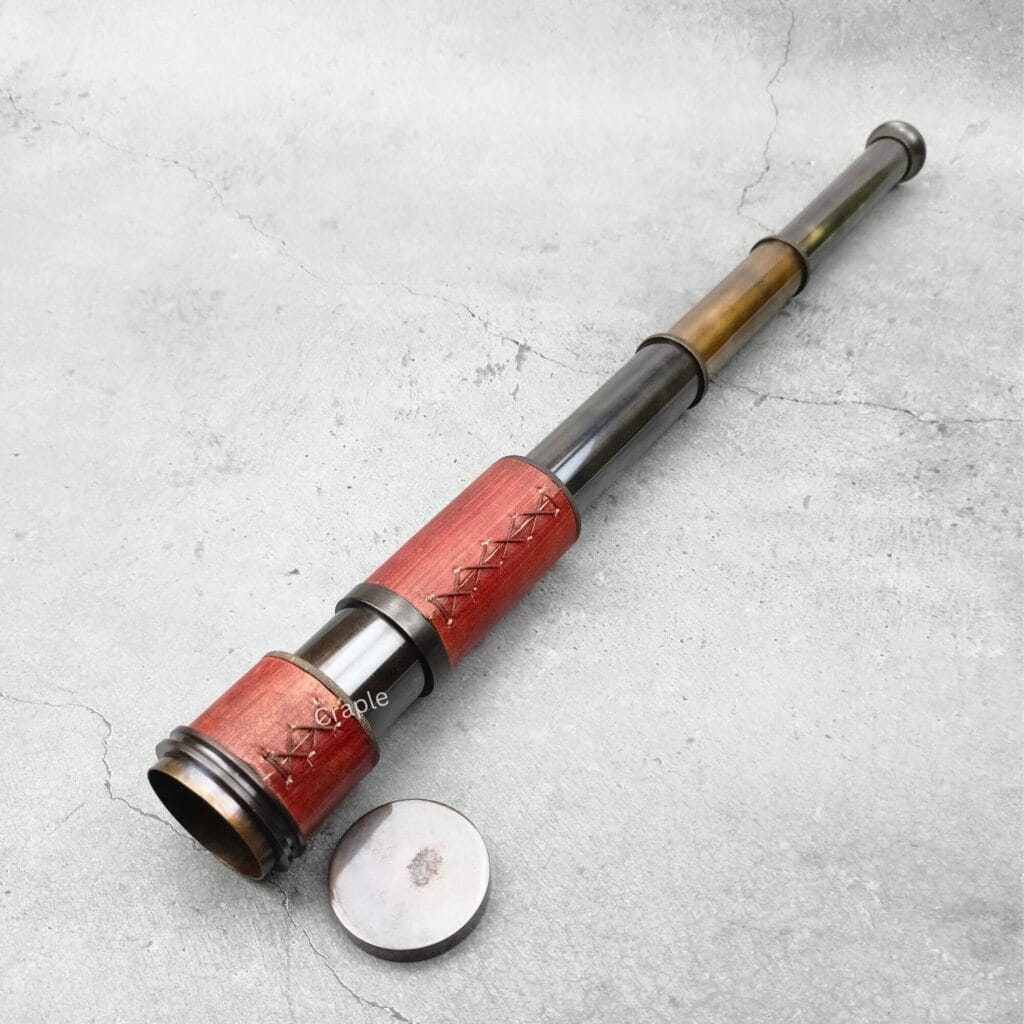 Vintage-style brass and leather spyglass telescope fully extended, with its brass lens cap on the side.