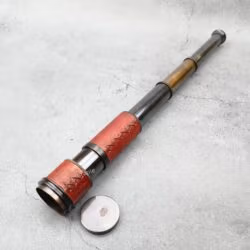 Vintage-style brass and leather spyglass telescope fully extended, with its brass lens cap on the side.