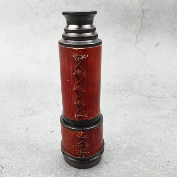 Close-up of the collapsed pirate-style telescope, showing the detailed cross-stitching on the red leather.