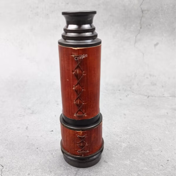 Close-up of the collapsed pirate-style telescope, showing the detailed cross-stitching on the red leather.