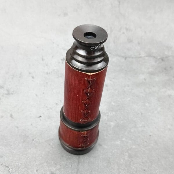 The compact, leather-wrapped brass telescope in a collapsed state, showing the eyepiece.