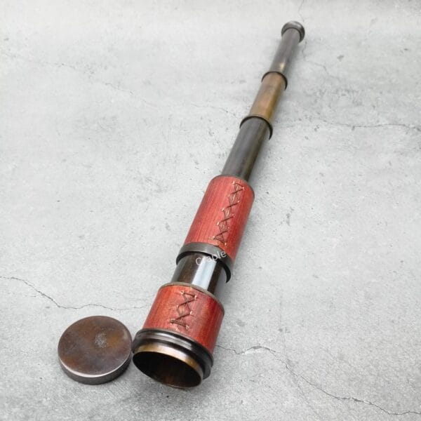 The fully extended 15.75-inch nautical spyglass showing its antique brass barrels and red leather grip.