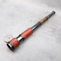 A full view of the extendable pirate-style brass telescope with its lens cap on the ground.