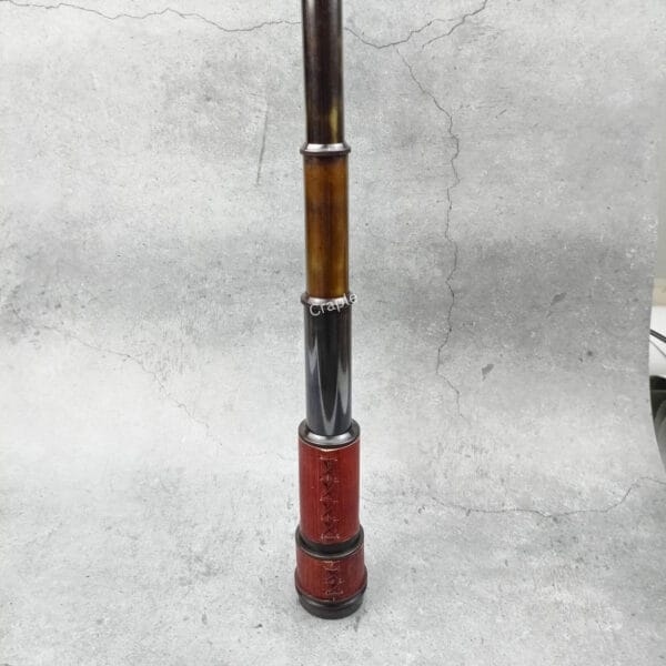 The vintage brass telescope standing flat at its full extension, showcasing all its collapsible sections.