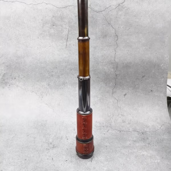 The vintage brass telescope standing flat at its full extension, showcasing all its collapsible sections.