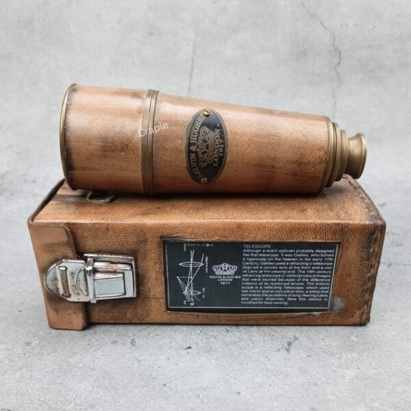 The antique brass and leather Kelvin & Hughes spyglass shown collapsed on top of its vintage-style leather box.