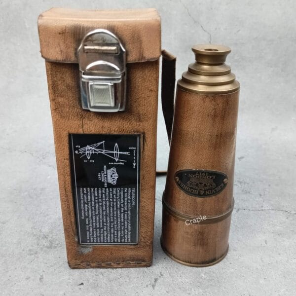 The Kelvin & Hughes brass telescope standing next to its upright leather case, showing the side plaque.