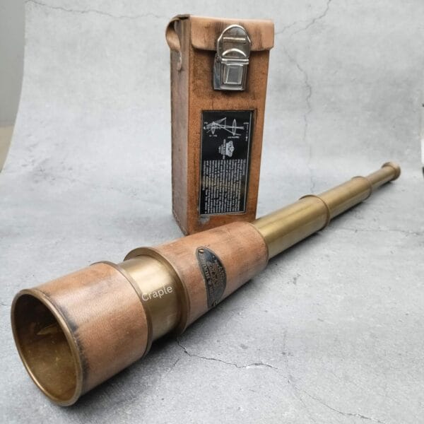 The leather-wrapped brass telescope partially extended, with its vintage leather case standing behind it.