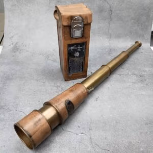 A fully extended Kelvin & Hughes antique brass telescope displayed next to its vintage brown leather carrying case.