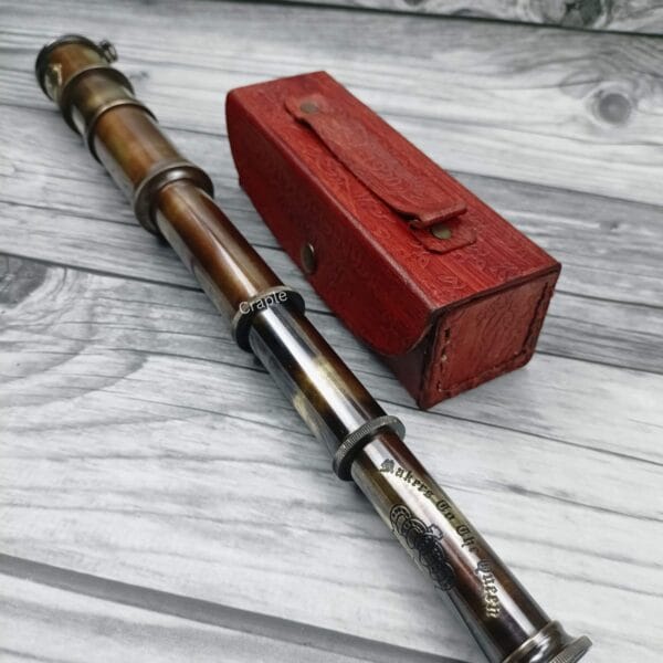 Fully extended 16-inch Royal Navy spyglass with an antique brass finish, shown lying next to its red leather case.