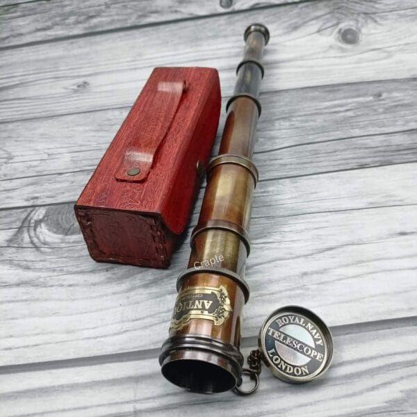 Close-up of the antique brass telescope's eyepiece, showing the "Royal Navy Telescope London" inscription on the lens cap.