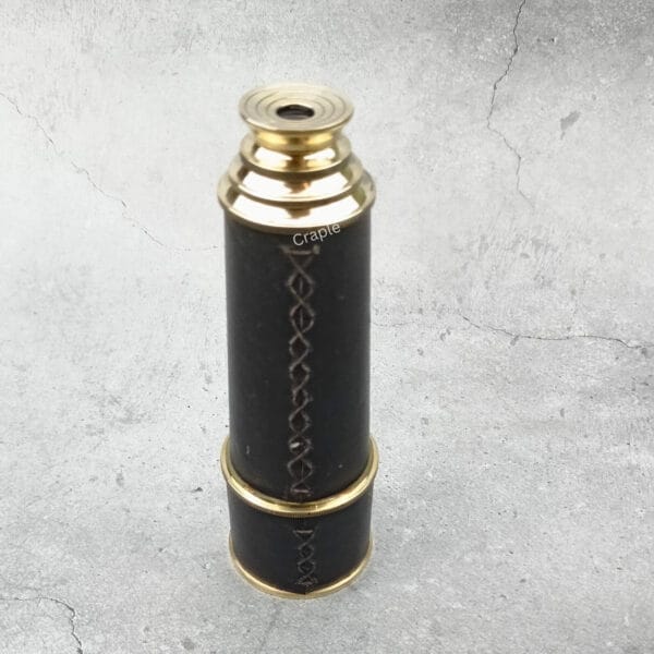 The collapsible nautical telescope in its compact, closed position, showing the hand-stitched leather detail.