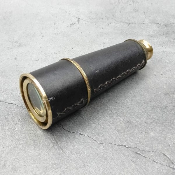 The compact, leather-wrapped brass telescope shown collapsed, focusing on the objective lens.
