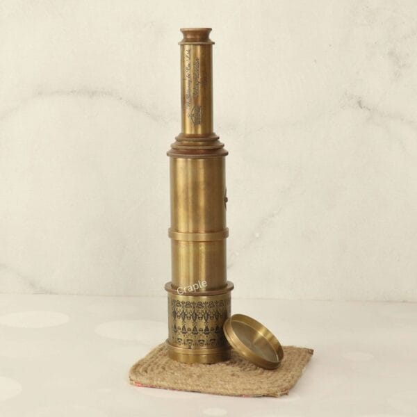 Partially collapsed antique brass telescope standing vertically, with its lens cap removed to the side.