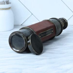 The vintage leather and brass spyglass telescope shown in its fully collapsed position with the antique brass lens cap on.