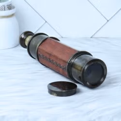 Angled view of the collapsed antique brass telescope, showing the objective lens and the rich texture of the leather wrap.