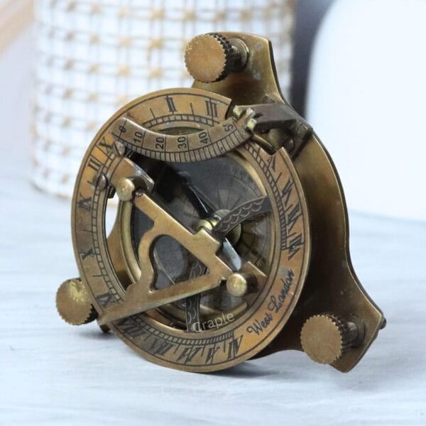 Side profile of the vintage brass sundial compass, showing the adjustable leg screws and antique finish.