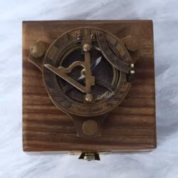 The brass sundial compass nestled inside its protective wooden display case with a velvet interior.
