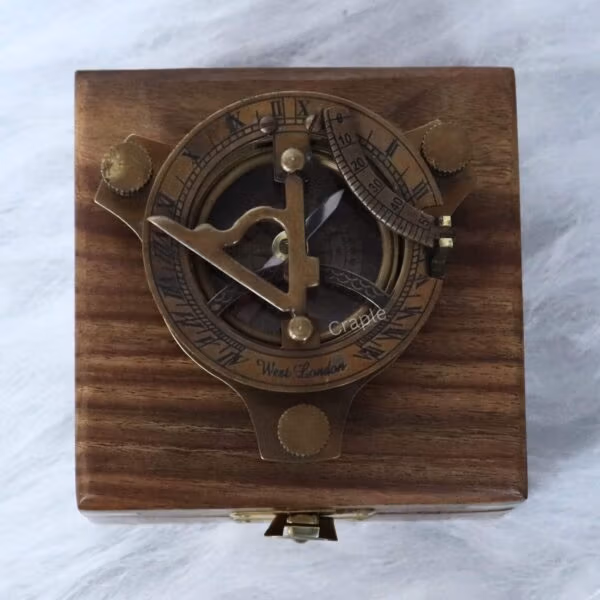 The brass sundial compass nestled inside its protective wooden display case with a velvet interior.