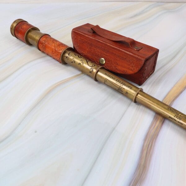 Antique-style brass and leather telescope, fully extended, lying next to its handcrafted wooden and leather storage case.