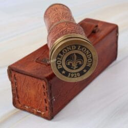The compact, collapsed brass telescope with its leather grip, shown next to the vintage-style stitched leather case.