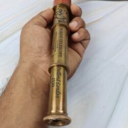 A hand holding the extended brass marine telescope, showing the engraved "Dollond London" text along the barrel.
