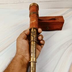 A hand gripping the collapsed nautical telescope by its hand-stitched, embossed leather section.