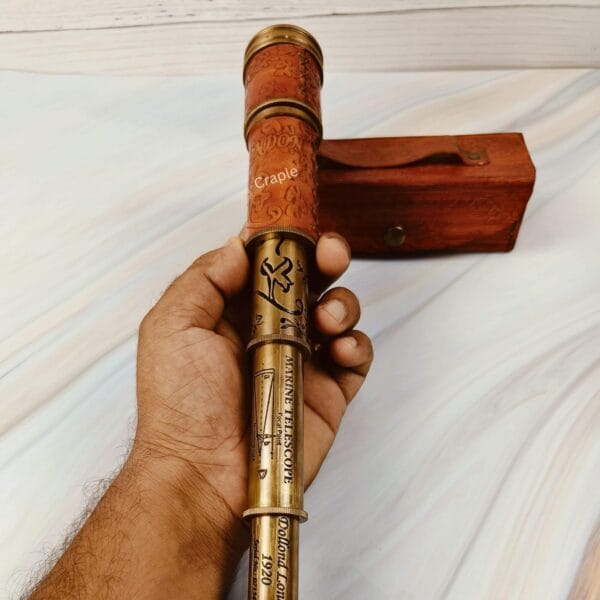 A hand gripping the collapsed nautical telescope by its hand-stitched, embossed leather section.