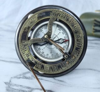 Antique brass and silver sundial compass with a foldable gnomon, displayed as a vintage decorative piece.