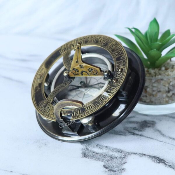 Antique Brass-Silver Sundial Compass-4 The two-tone brass and silver sundial compass displayed as a stylish desktop accessory next to a small plant.