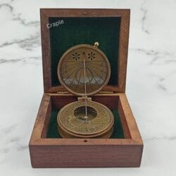 Antique brass string sundial compass displayed open inside its green felt-lined wooden gift box.